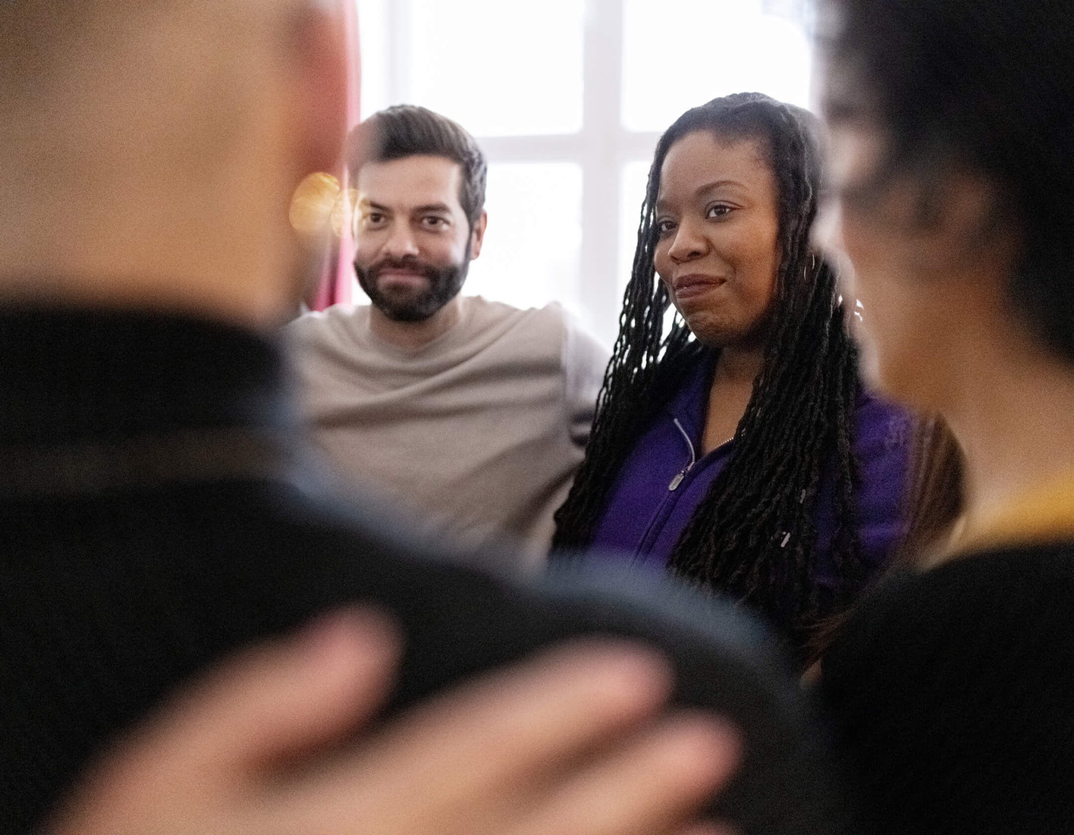 A diverse group of individuals gathered around a man and woman, engaged in conversation and sharing smiles.