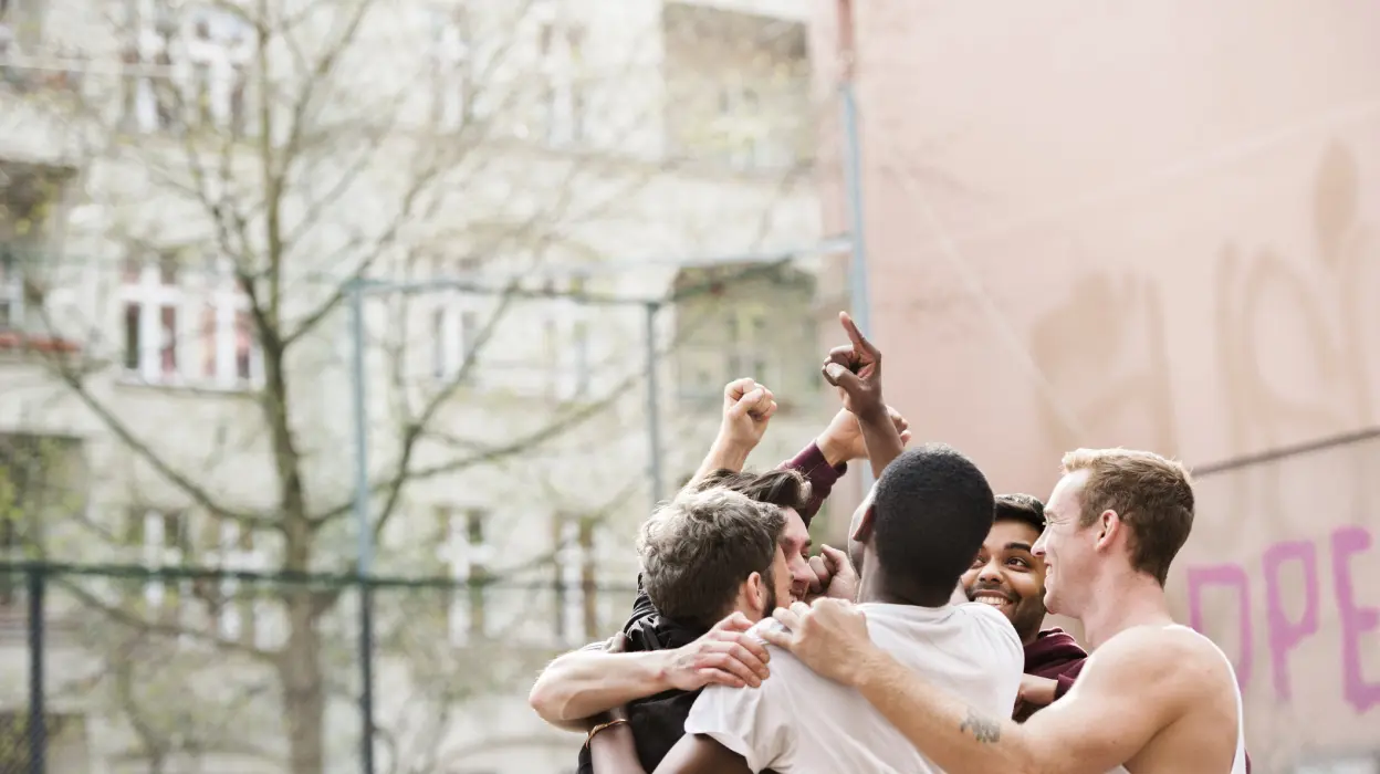 A group of men standing together, engaged in conversation, showcasing camaraderie and unity in a social setting.