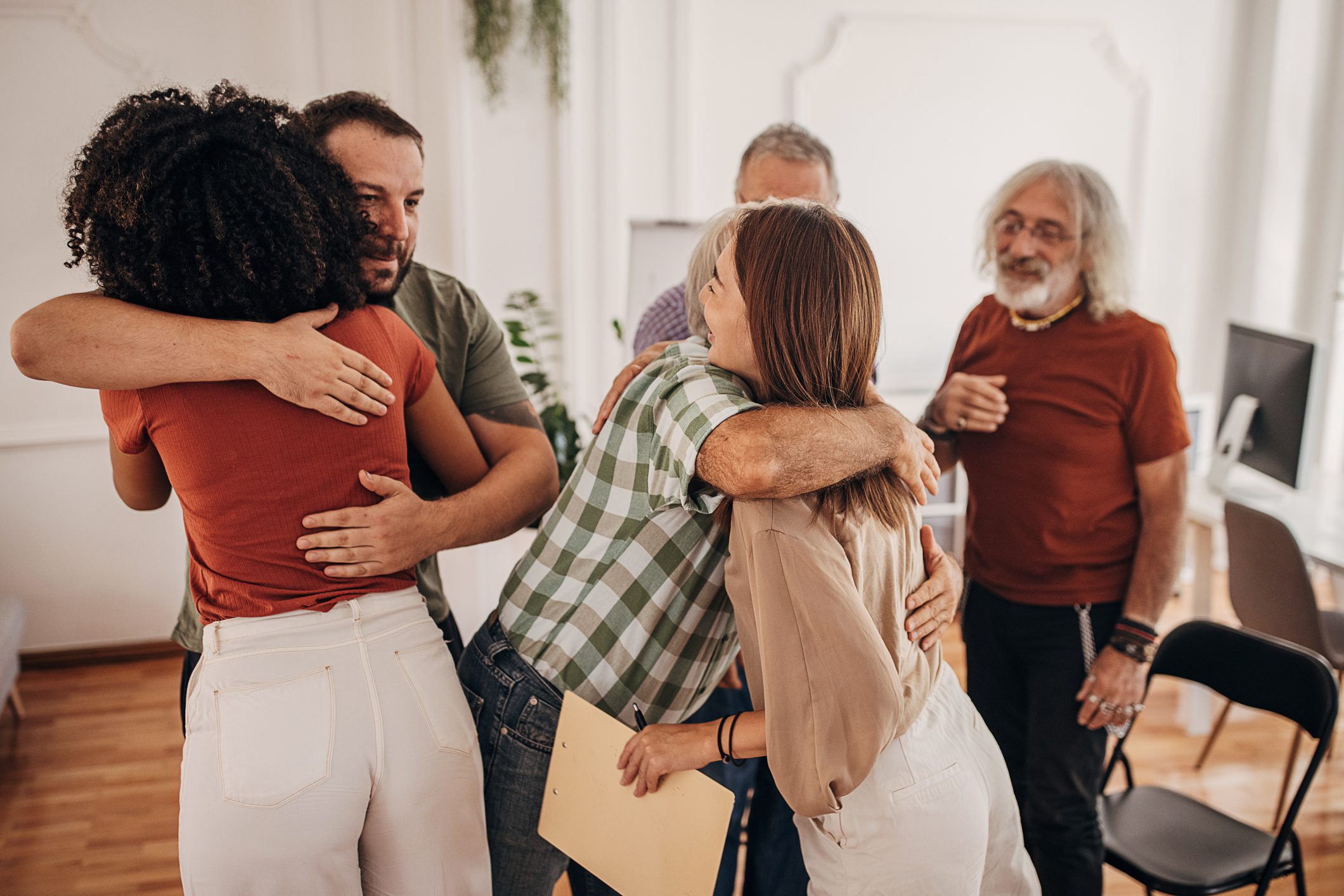 A group of people embracing each other warmly in a cozy living room setting, showcasing friendship and connection.