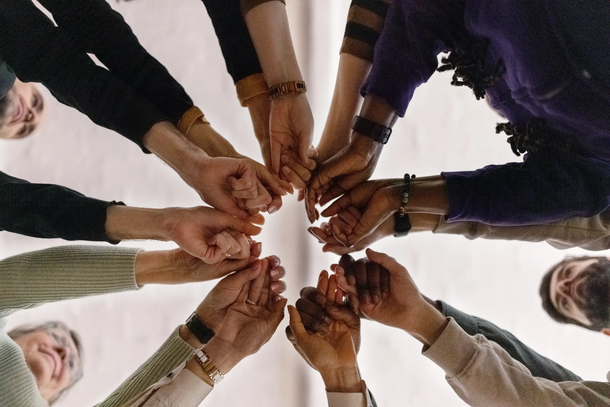 A diverse group of individuals standing in a circle, holding hands, symbolizing unity and togetherness.