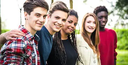 A group of individuals seated in a circle, each placing their hands on the shoulders of the person next to them.